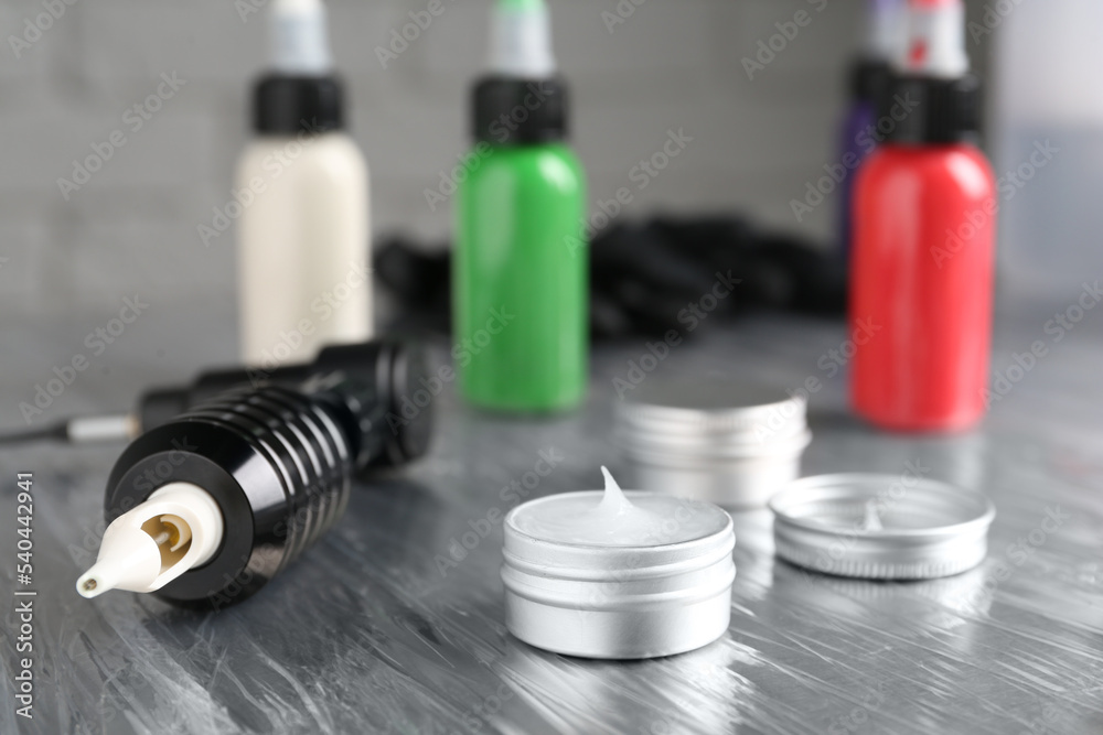Modern professional tattoo machine and ointment on table in salon Modern professional tattoo machine and ointment on table in salon