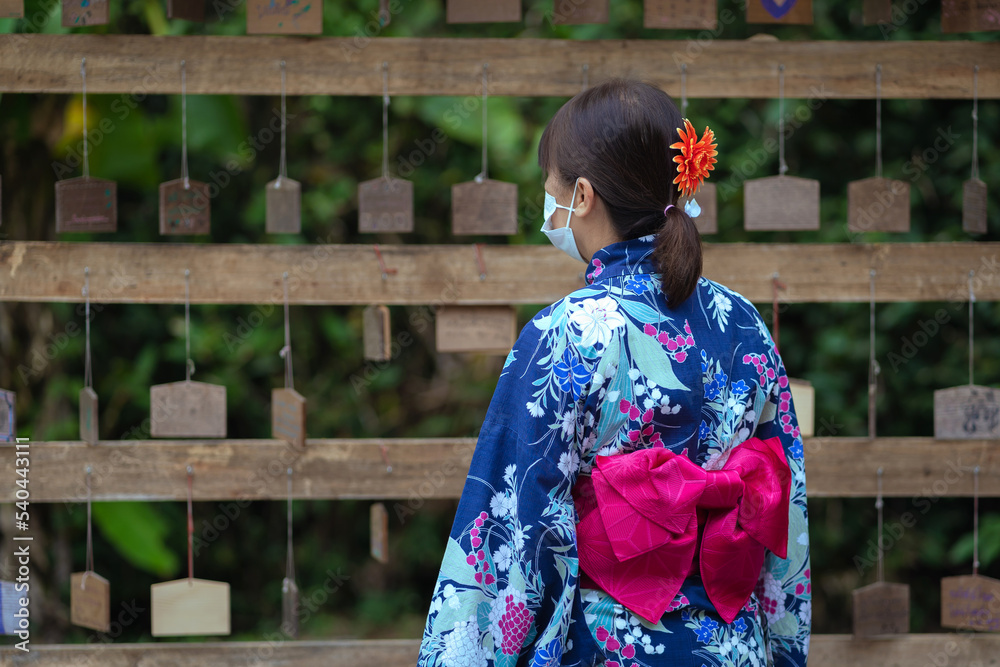 Japanese women with masks beautiful dresses Yukata Kimono and red umbrellas wear traditional clothes and stand hold a red umbrella and wall for hanging wooden signs wishing sacred things. Japanese women with masks beautiful dresses Yukata Kimono and red umbrellas wear traditional clothes and stand hold a red umbrella and wall for hanging wooden signs wishing sacred things.