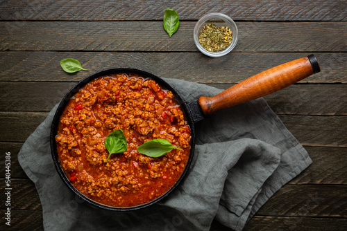 Overhead view of red meat sauce in skillet pan on textile rustic