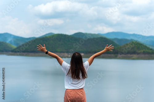 Woman rise her hands up to sky with mountain and water in Chiangmai Thailand for freedom, success and travel concept.