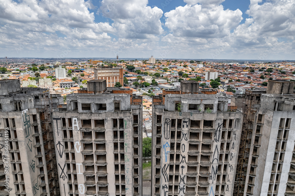 Abandoned buildings in the city of Campinas, countryside of São Paulo. Vegetation, construction debris and vehicles circulating around the residential neighborhood.