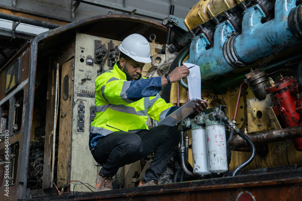 Engineer checking train engine Prepare for repainting for use in train stations. Engineers wear protective clothing and helmets to work safely as standard.