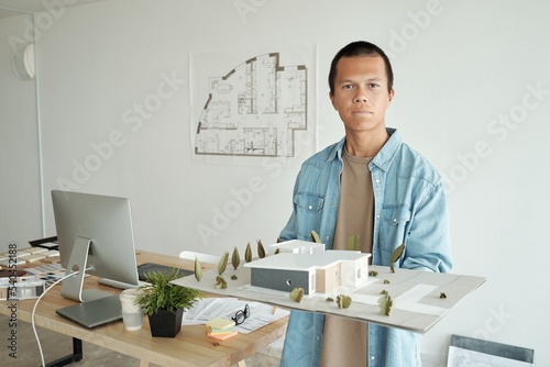 Принти на полотні Photo realistic digital collage of young confident architect holding house layou