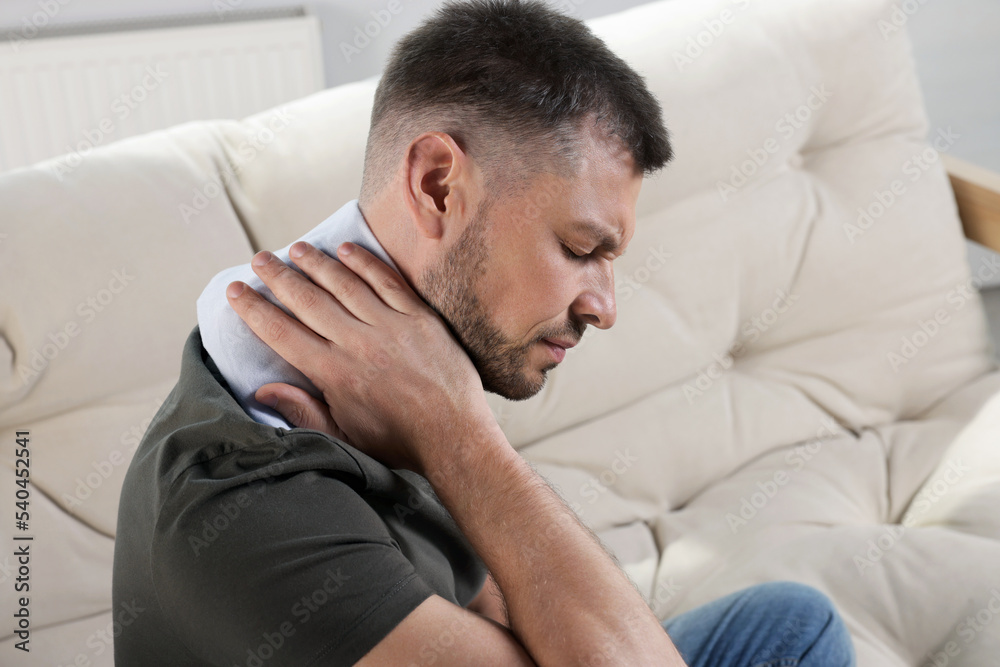 Man using heating pad on sofa at home