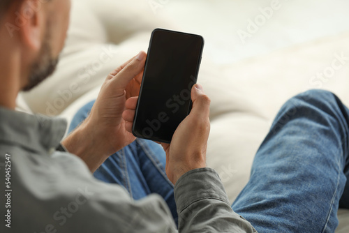 Man using smartphone indoors, closeup of hands