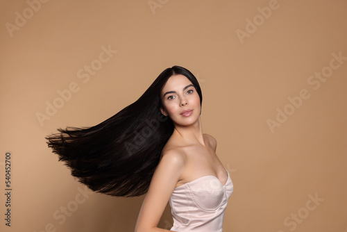 Portrait of beautiful young woman with healthy strong hair on beige background