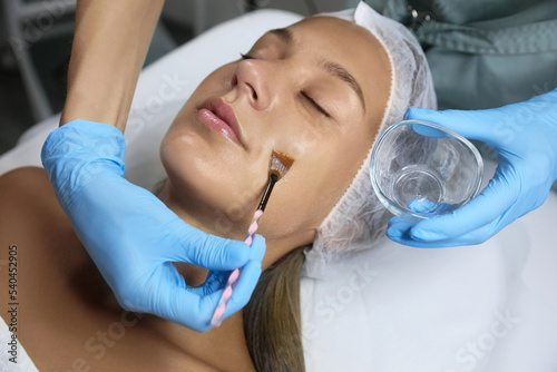 Cosmetologist applying chemical peel product on client s face in salon