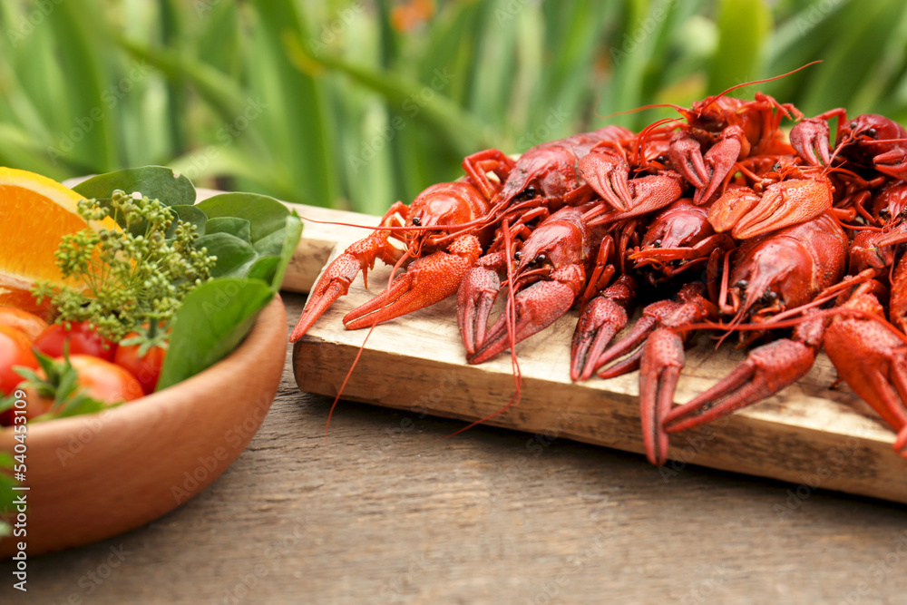 Delicious red boiled crayfish and products in bowl on wooden table Delicious red boiled crayfish and products in bowl on wooden table