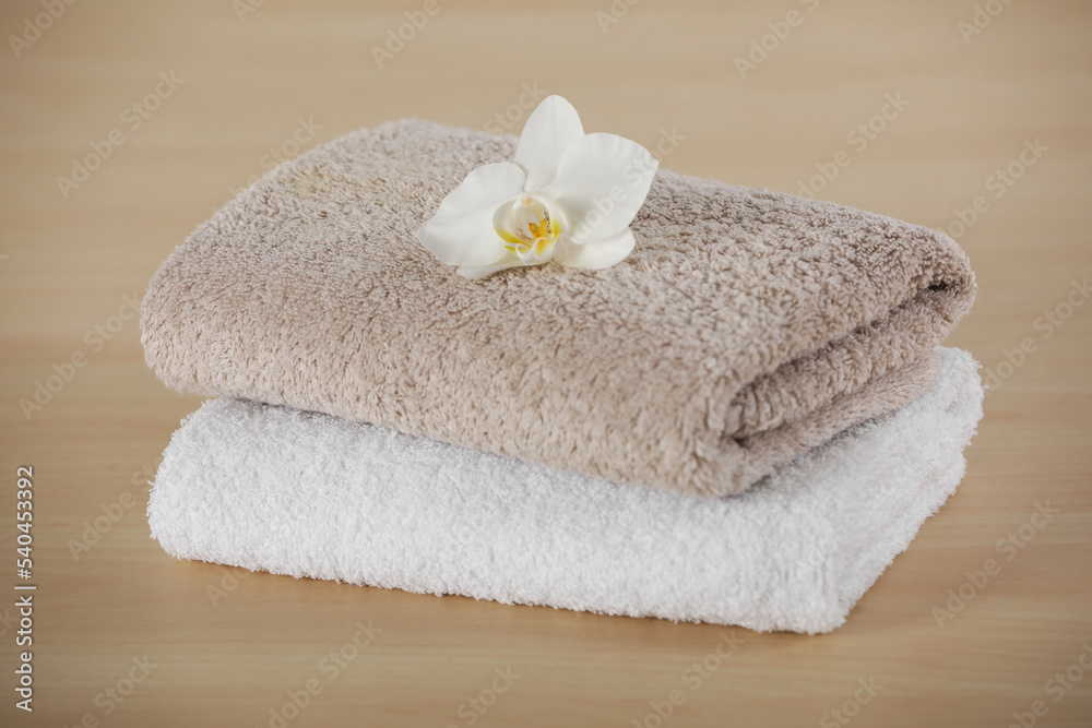 Soft folded towels with orchid flower on wooden table Soft folded towels with orchid flower on wooden table