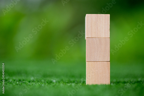 Stacking blank wooden cubes on green background with copy space for input wording and infographic icon. Empty brown wooden object block for symbol icon put technology, zero gravity, business concept.