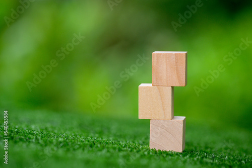 Stacking blank wooden cubes on green background with copy space for input wording and infographic icon. Empty brown wooden object block for symbol icon put technology, zero gravity, business concept.