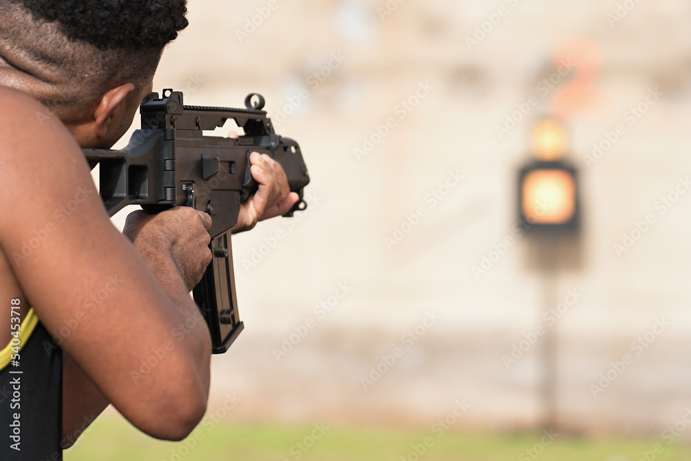 Man holding a black rifle to target shooting at a shooting range with an automatic weapon