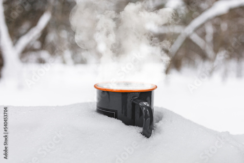 Cup of hot beverage with steam on the snow