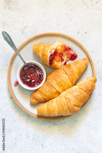 Croissants with jam on a plate on a light concrete background close-up centered