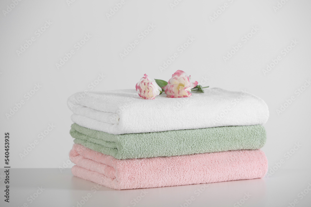 Soft folded towels with eustoma flowers on white table Soft folded towels with eustoma flowers on white table