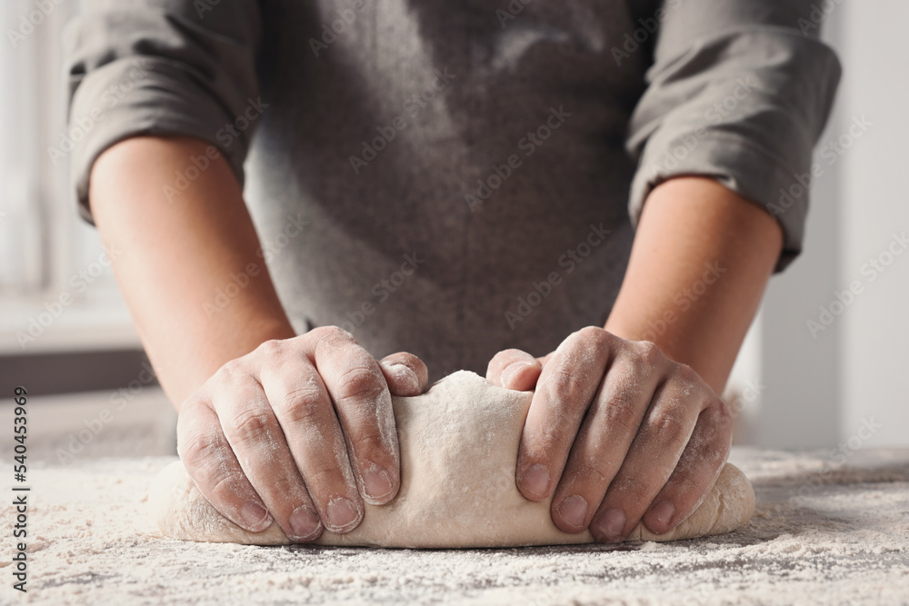 Man kneading dough at table in kitchen, closeup Man kneading dough at table in kitchen, closeup