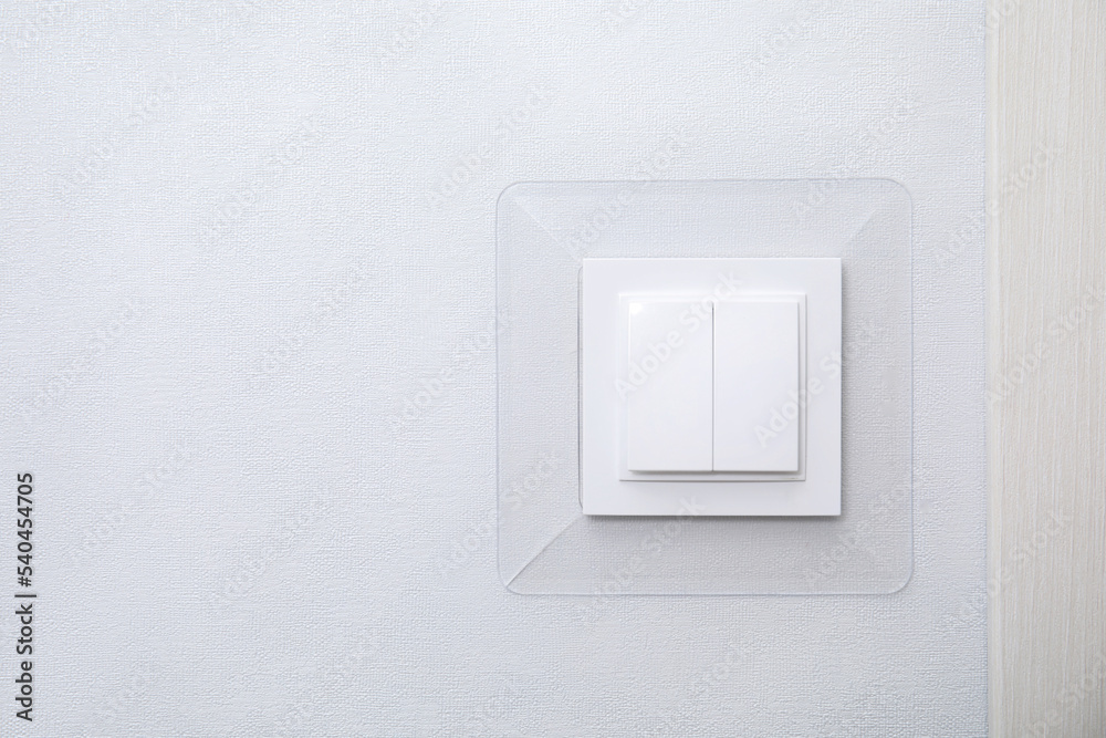 Modern plastic light switch on white wall, space for text Modern plastic light switch on white wall, space for text