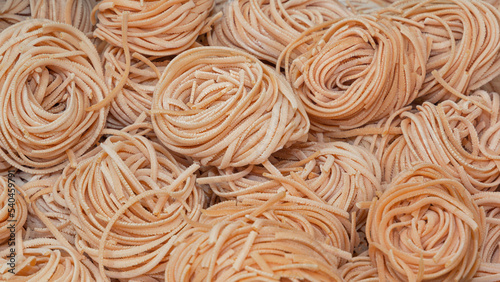 Raw linguini pasta sold in open bags at a street fair. Close-up