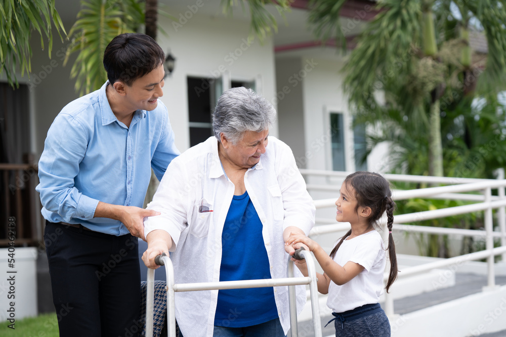 Young man and granddaughter who cares Smiling elderly woman happily on a wheelchair in the park