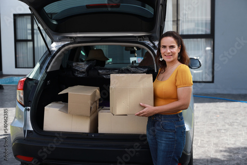 Happy young caucasian family carry boxes from car and entering new house together