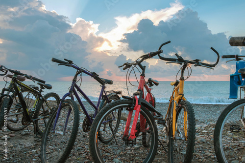 Fototapeta Naklejka Na Ścianę i Meble -  The row of bikes on the beach wit blue cloudy sky and sea background