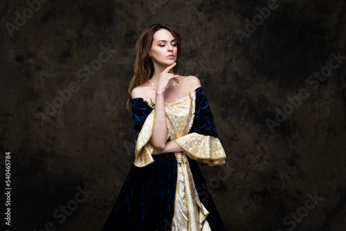 Beautiful woman in renaissance royal dress on abstract dark background