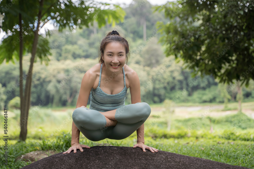 young woman practicing yoga beside a mountain by a stream in the morning.
