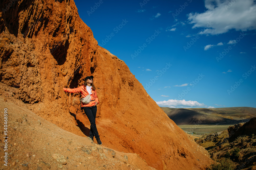 Happy young woman tourist admires red canyon. Brave female hiker in mountains solo trekking. Adventure, wanderlust, sightseeing. Happy young woman tourist admires red canyon. Brave female hiker in mountains solo trekking. Adventure, wanderlust, sightseeing.