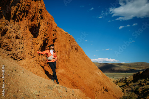 Happy young woman tourist admires red canyon. Brave female hiker in mountains solo trekking. Adventure, wanderlust, sightseeing.