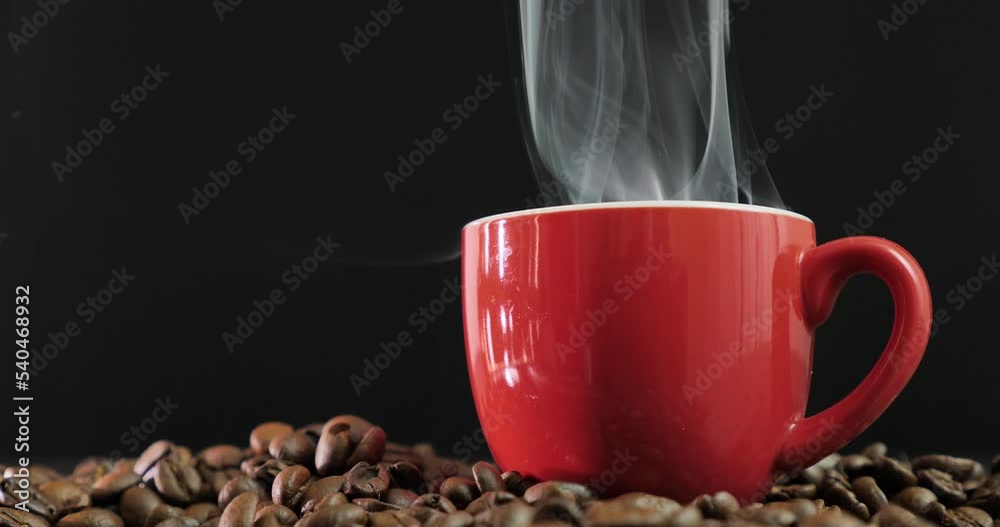 Tazzina di caffe caldo fumante e chicchi di caffè sul tavolo