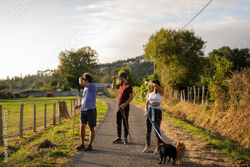 Photography Three people observing the landscape in the nature at sunset with two dogs