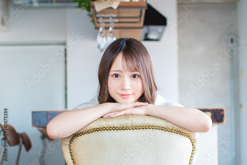 イスから覗き込むようにこちらを見つめる日本の若い女性