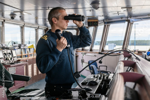 Fototapeta Deck officer with binoculars on navigational bridge
