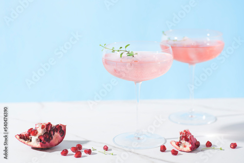 Winter holidays festive alcohol pink cocktails with peace of pomegranate in the marble table, winter drink concept, New Year holidays, front view