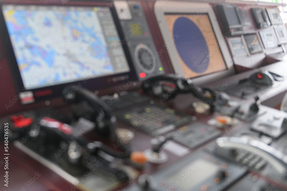 Navigational control panel and VHF radio. Working on the ship's navigational bridge. Blurred image. Navigational control panel and VHF radio. Working on the ship's navigational bridge. Blurred image.