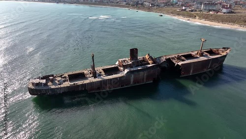 Flight over the shipwreck. 4K Aerial drone shot. A lone old ship wreck in the middle of the sea. Birds fly around the ship. photo