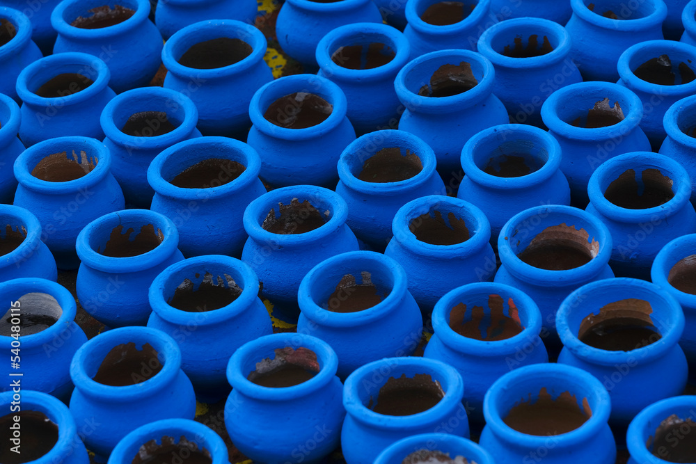 Artisan painting earthen pots, A background of colorful pots used for rituals during Diwali festival in India.