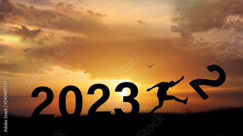 Young man kicking number 2 of the year 2022 to welcome the year 2023 in a happy celebration. with birds flying on top of the mountain On the gaps of the hills with independent challenges
