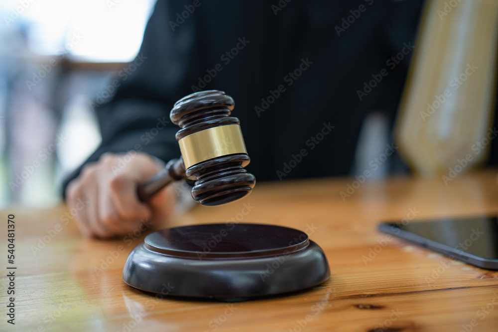 Woman judge hand holding gavel to bang on sounding block in the courtroom.
