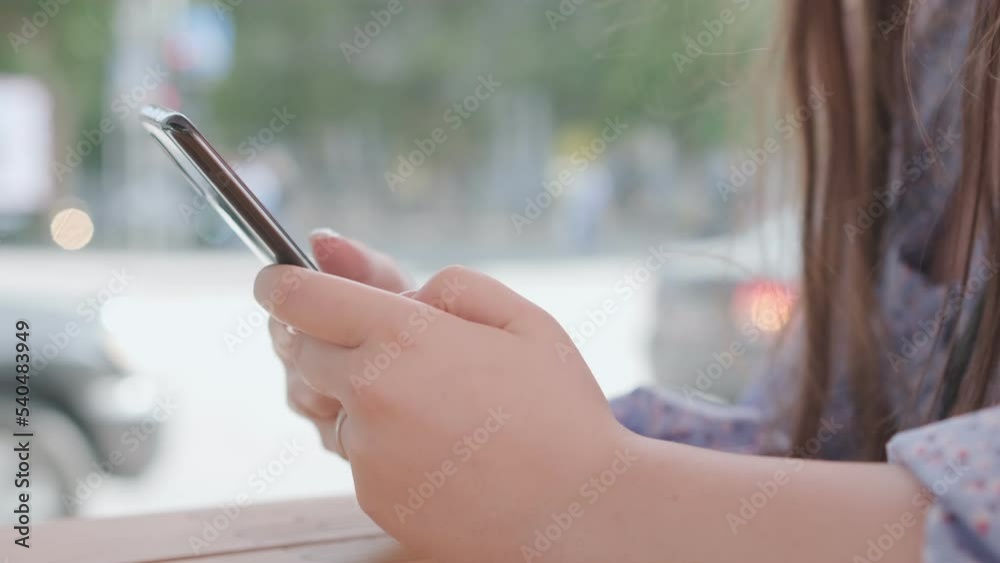 Women holding cell phone using smartphone device in a street cafe. Woman blogger subscribing new social media, buying in internet, ordering products online in apps. Women holding cell phone using smartphone device in a street cafe. Woman blogger subscribing new social media, buying in internet, ordering products online in apps.