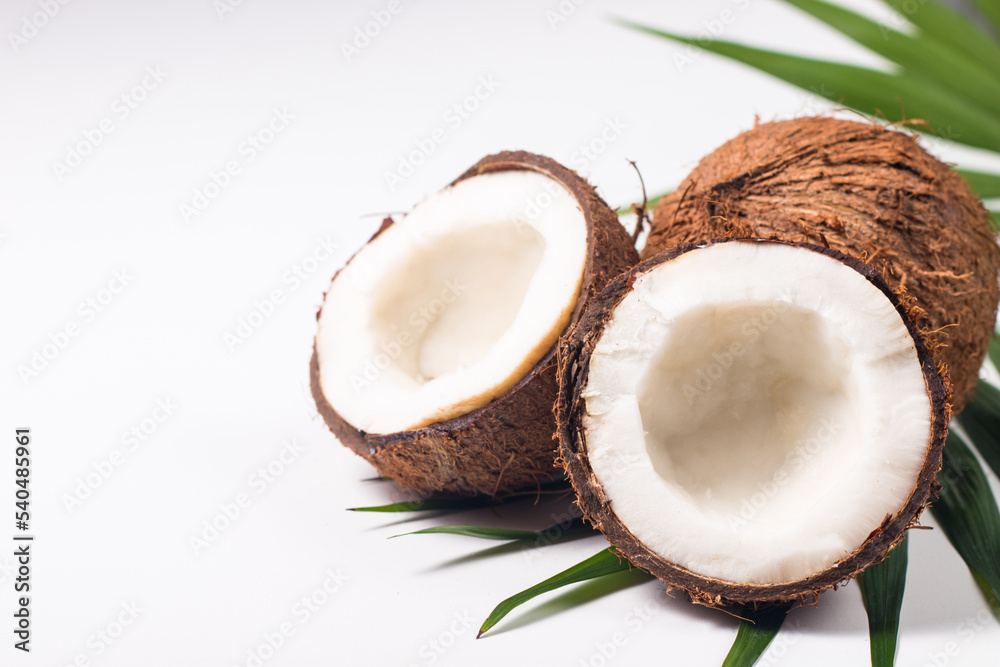 Ripe half cut coconut with green leaves on a white background. Isolated concept. Ripe half cut coconut with green leaves on a white background. Isolated concept.