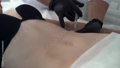 Cosmetic injection in spa salon. Beautician makes injection into the female belly. Beautician makes the patient anti-cellulite injection. Close-up. Cosmetology photo