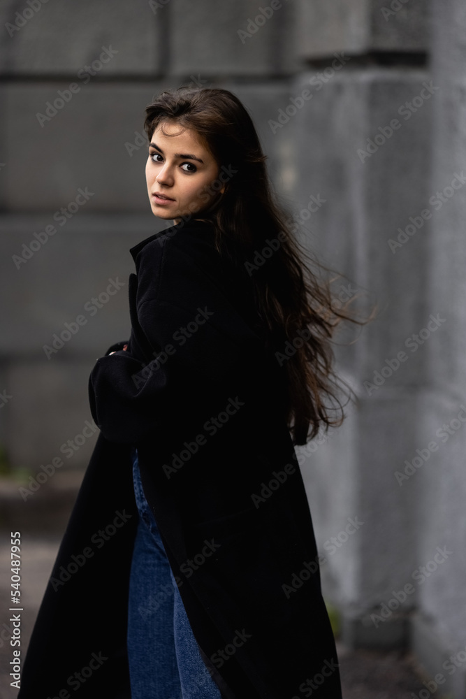 Fototapeta premium A young beautiful woman in a black coat