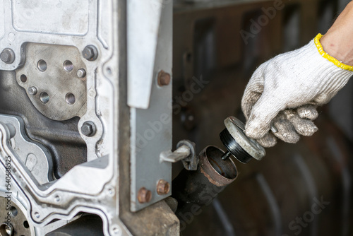 Mechanic man holding engine oil fill cap of diesel commonrail engine in heavy machinery workshop