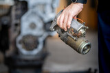 Mechanic man holding starter motor of diesel commonrail engine in heavy machinery workshop