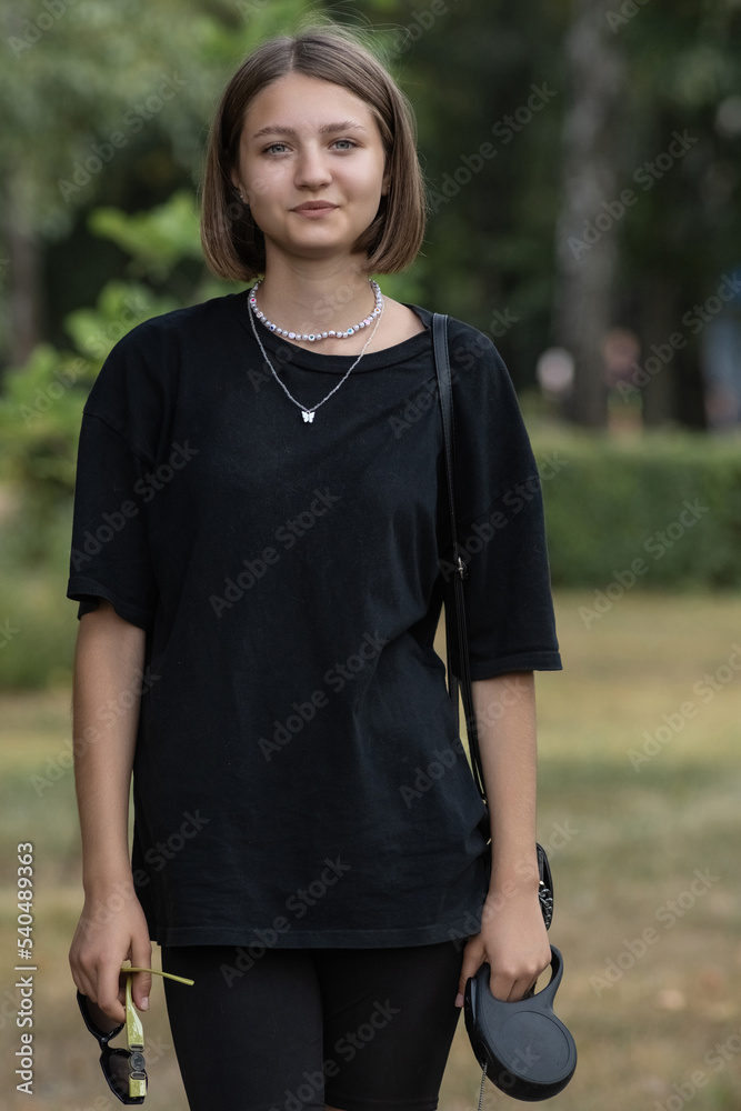Portrait of a young beautiful fair-haired girl in dark clothes in the city in summer. Portrait of a young beautiful fair-haired girl in dark clothes in the city in summer.