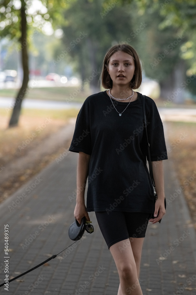 Portrait of a young beautiful fair-haired girl in dark clothes in the city in summer. Portrait of a young beautiful fair-haired girl in dark clothes in the city in summer.