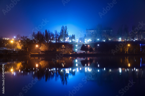Beautiful view of river and city with glowing lights at night © Pixel-Shot