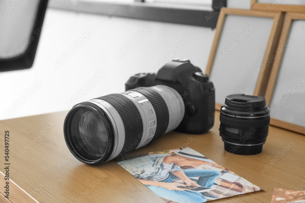 Professional photo camera and picture on table in office, closeup