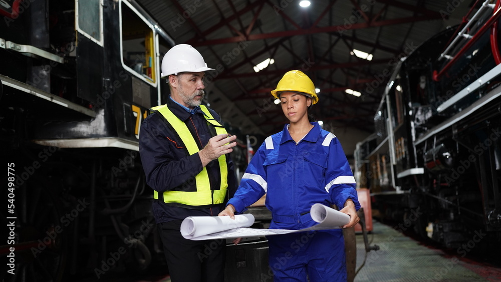 Fototapeta premium Group of apprentices with instructor at railway engineering facility. Teacher talking to apprentices at railway engineering facility